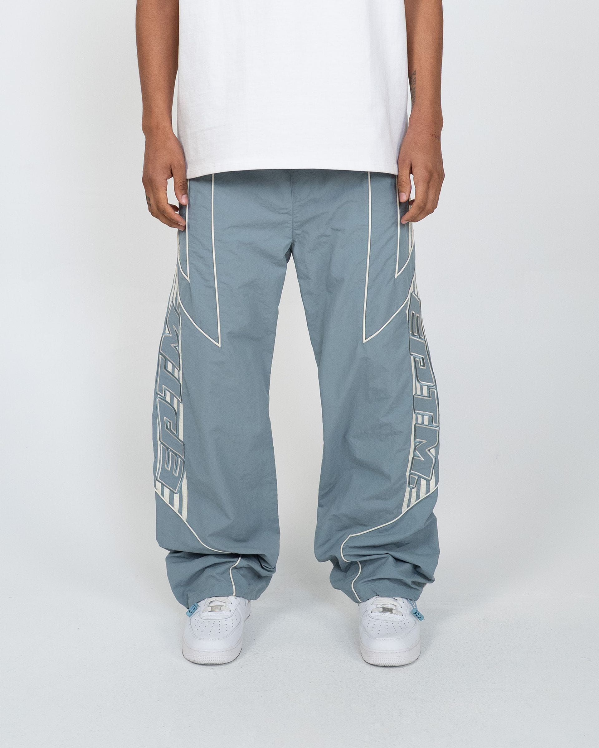EPTM Pepe track pants in black with white side stripes, made from comfortable athletic fabric, shown on a hanger.