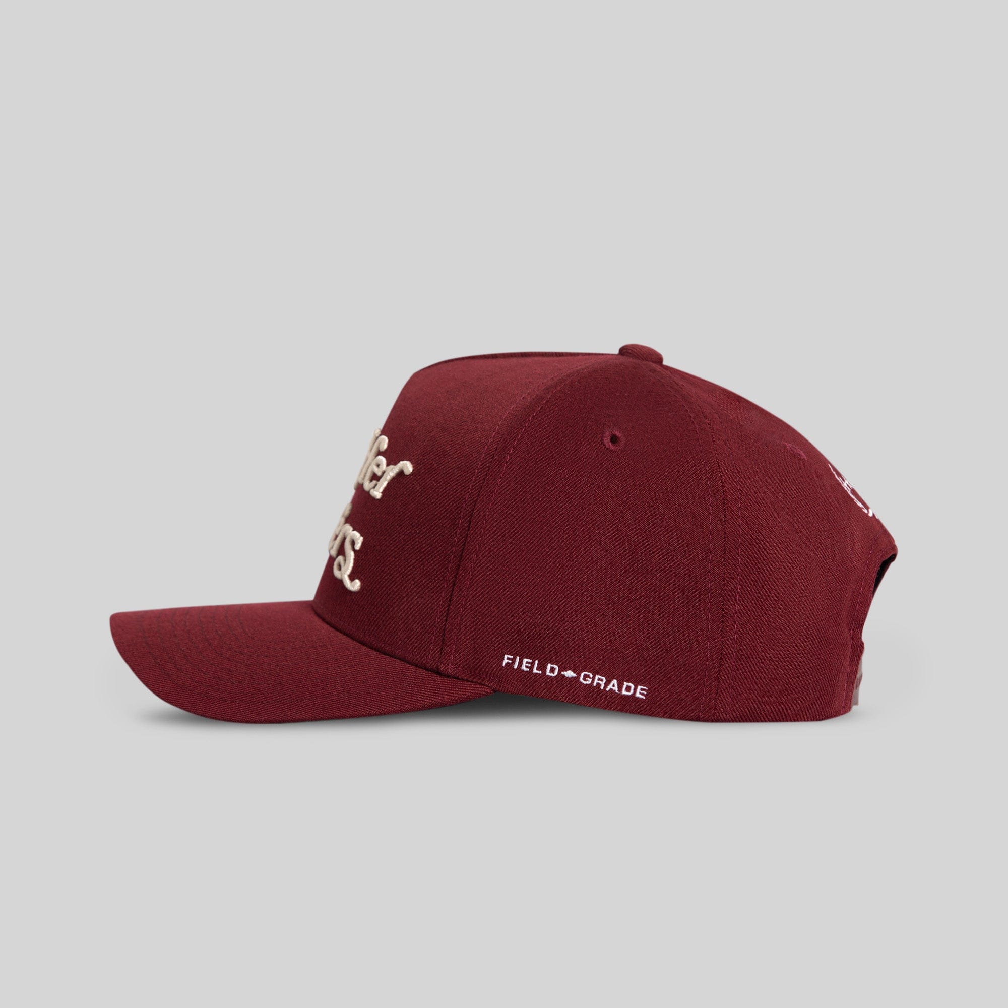 Field Grade Buy Her Flowers Bordeaux Wool Trucker hat with a classic brim and adjustable strap, shown from the side.