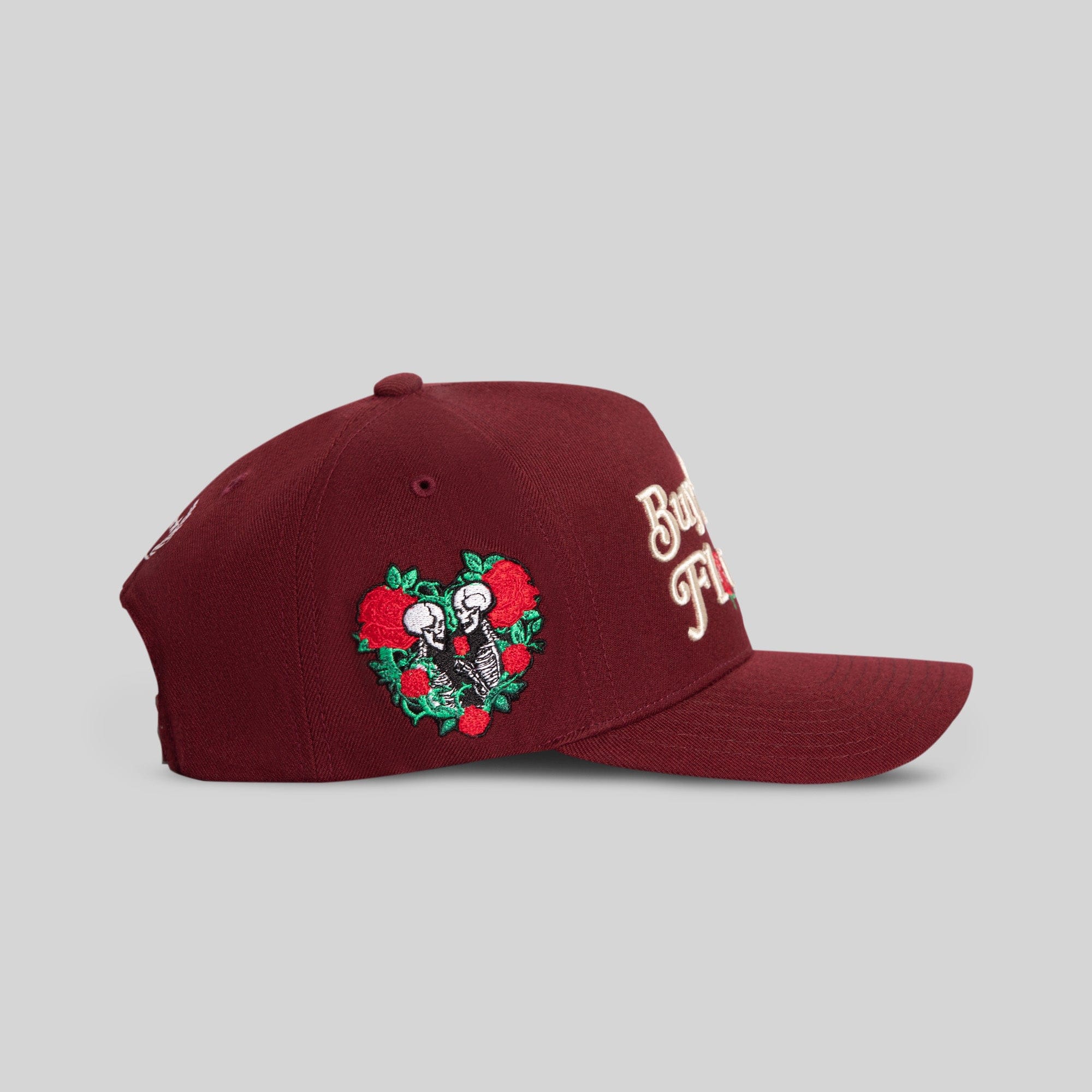 Field Grade Buy Her Flowers Bordeaux Wool Trucker hat showing the side view with a stylish brim and embroidered floral design.