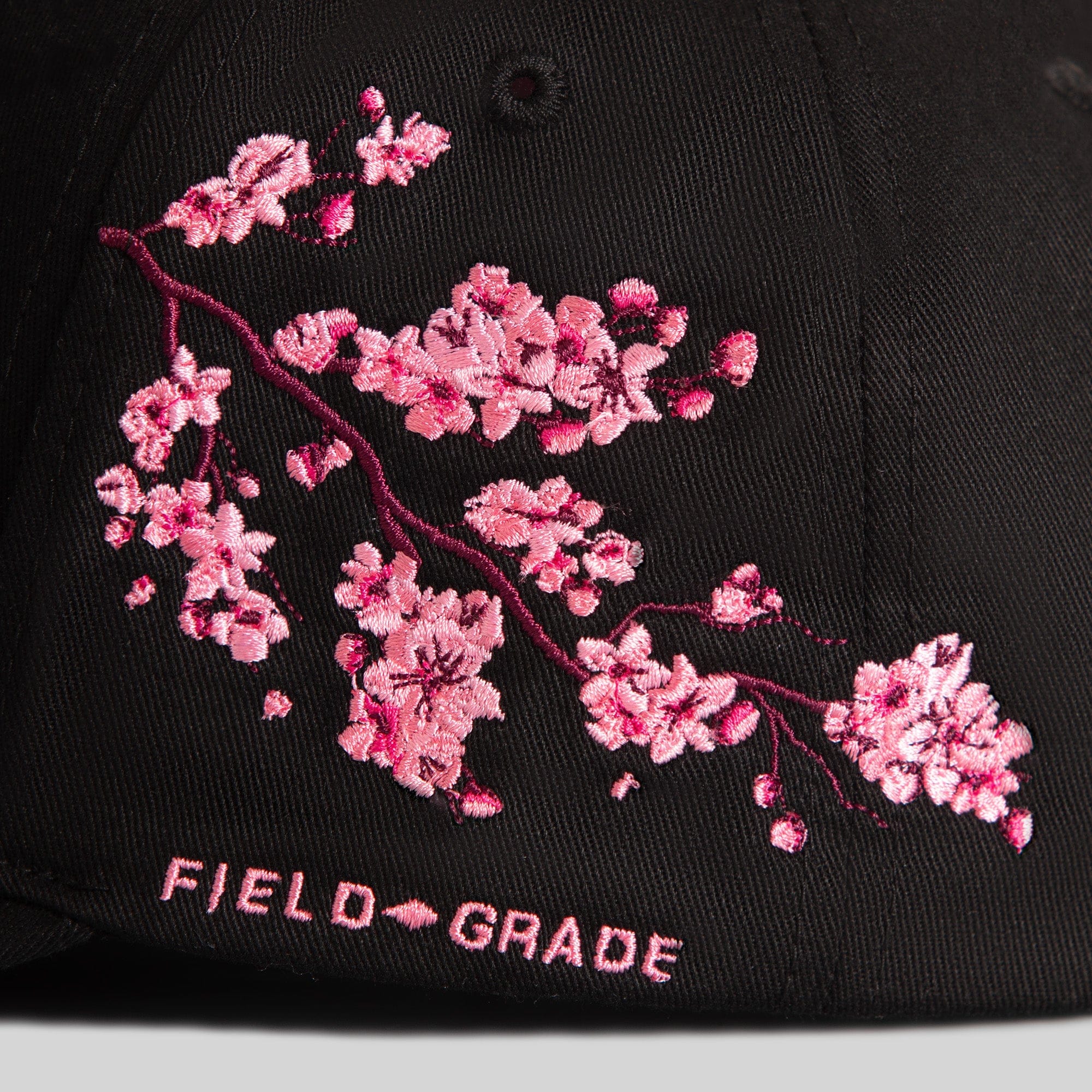 Field Grade cherry blossom black twill trucker hat featuring a curved brim and adjustable snapback closure.